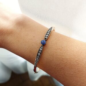 Bracelet jonc saphir « nœud » - XIXème siècle Photo portée sur le bras d'un bracelet jonc ancien en or jaune et argent, centré d'un saphir coussin bleu profond, épaulé de diamants taillés en rose, XIXe siècle