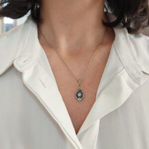 Pendentif Art Déco diamants et saphirs en forme de goutte, diamant central en serti griffes et entourage de saphirs bleus calibrés, platine et or gris.