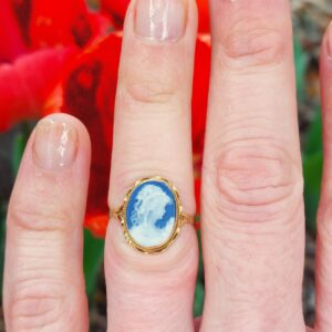 Photo portée d'une bague camée sur porcelaine bleue en or jaune 18k, centrée d'un camée figurant une élégante de profil, entourage festonné, style XIXe siècle
